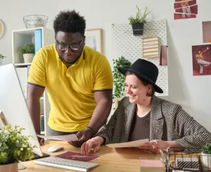 Two web developers sitting at a desk looking at a computer