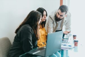 Group of colleagues engaging in a comprehensive analysis for a project around a laptop in an office setting.