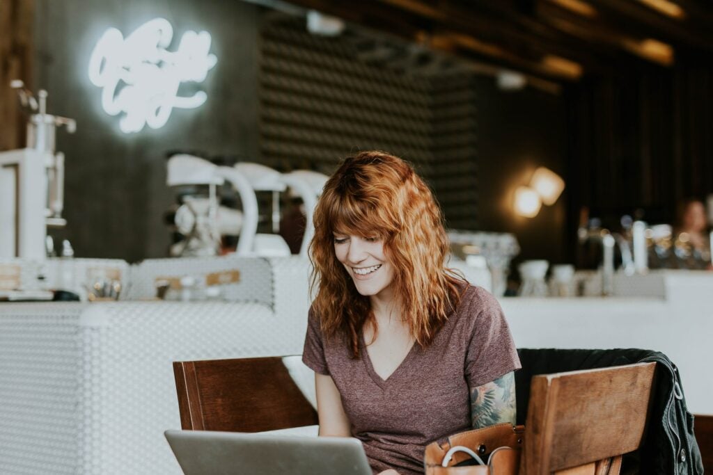 A woman working on a laptop in a coffee shop researching digital marketing earnings.