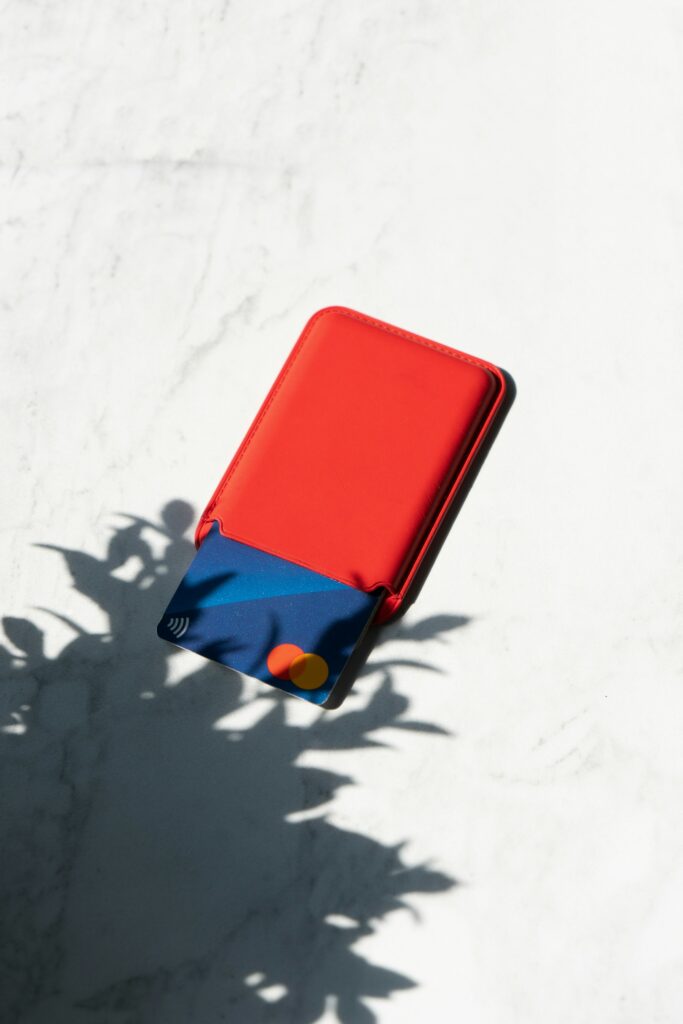 A Red Credit Card Sits On A White Surface, Promising Financial Freedom.