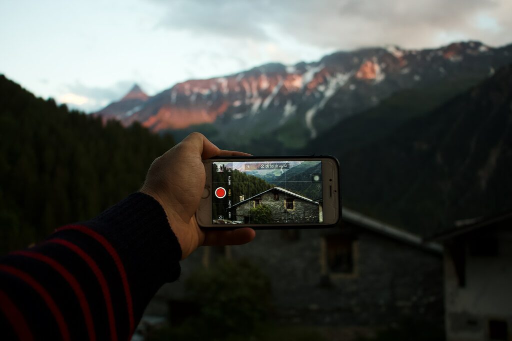 A person capturing a scenic mountain view with their smartphone.