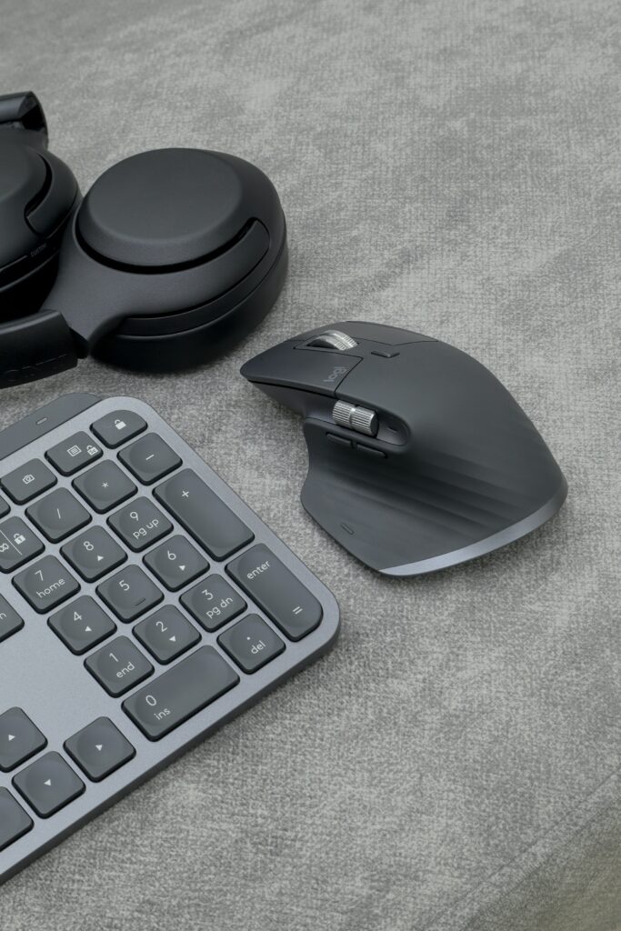 Wireless Keyboard, Clean Mouse Pad, And Headphones On A Gray Fabric Surface.