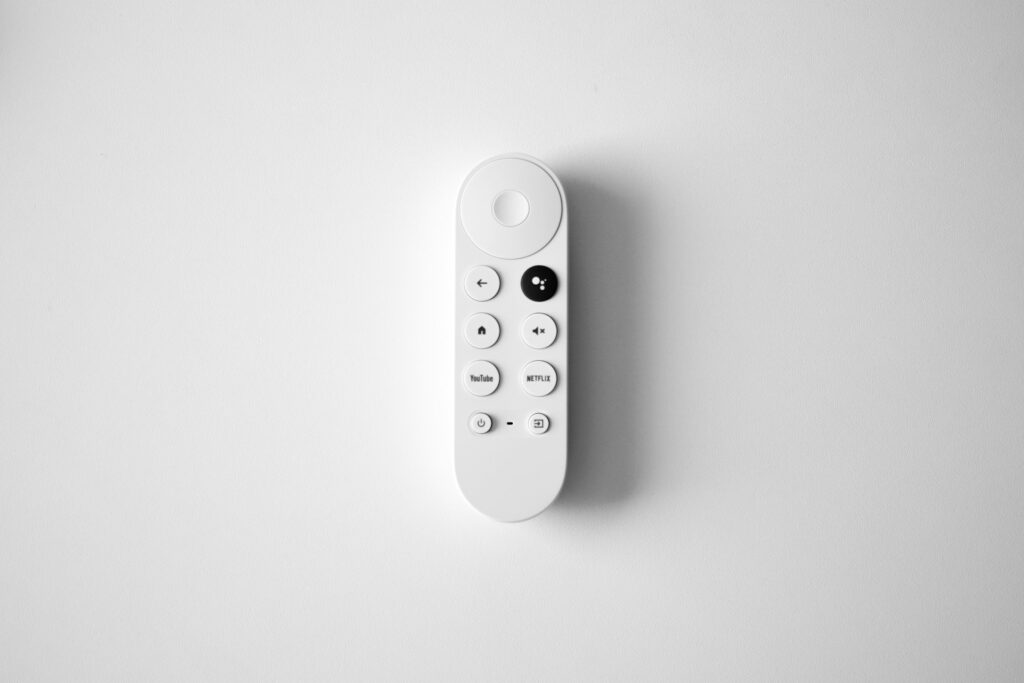 A white remote control on a white surface, designed to connect and guide users through WiFi setup for their Chromecast device.