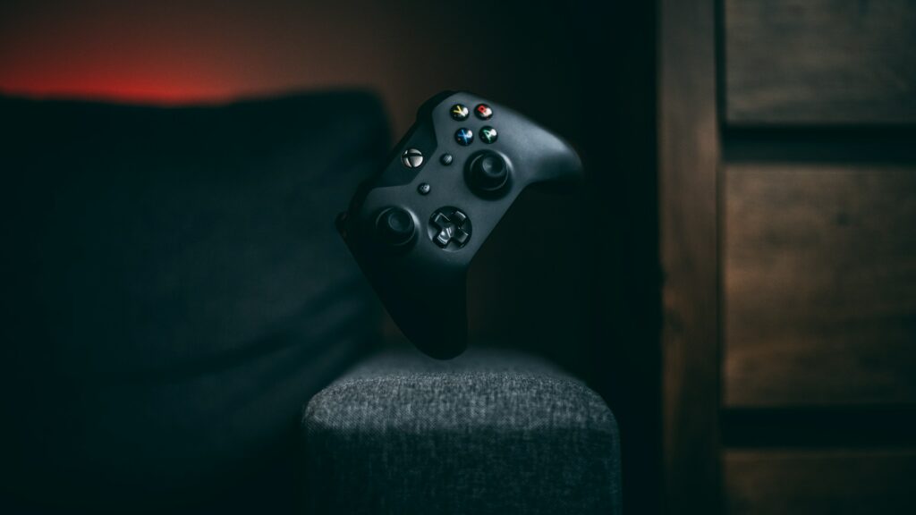 A black Xbox controller connected to a PC on top of a gray couch.
