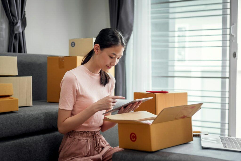 A woman mastering the art of decluttering while sitting on a couch surrounded by boxes, preparing to sell on Gumtree.