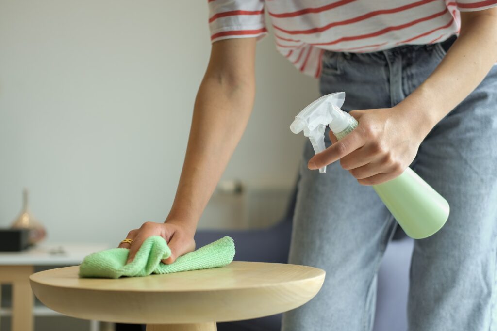 A woman starting a cleaning business, wiping a table with a green cloth.