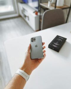 A hand holding an iPhone 11 Pro on a table, ready for AirDrop or sharing with a Mac.