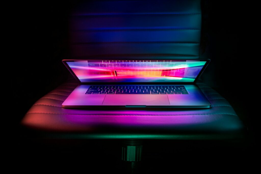 A laptop, used to unblock websites, is sitting on a chair in a dark room.