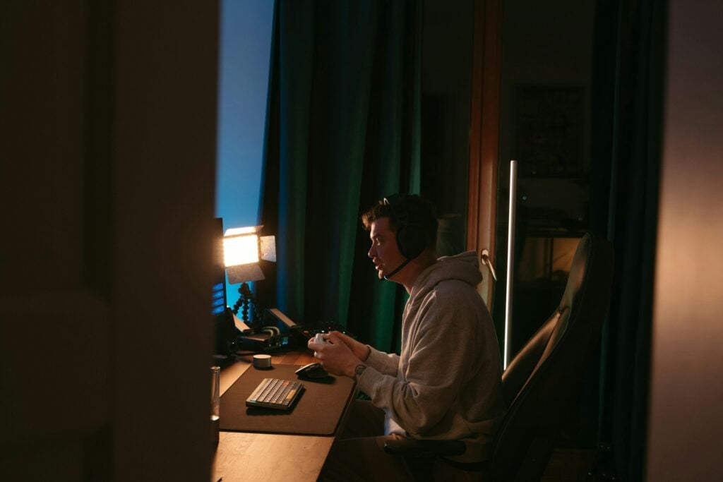 A Man Sitting In Front Of A Computer At Night, Searching For Instructions On How To Uninstall Valorant.