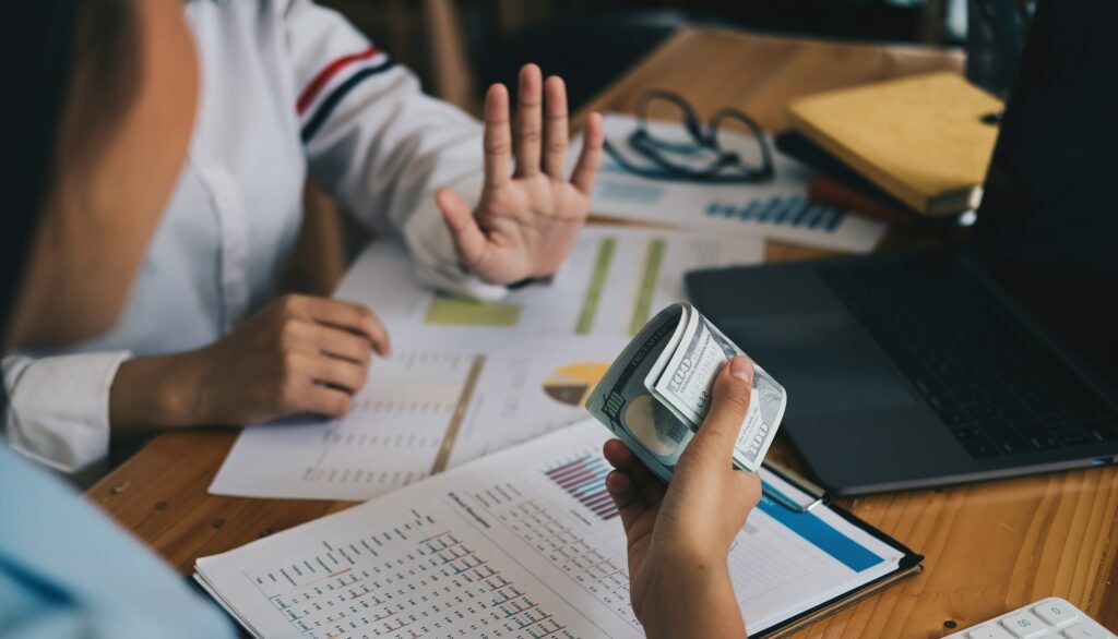 A woman sits at a desk with money and a laptop, diving into the world of digital marketing.