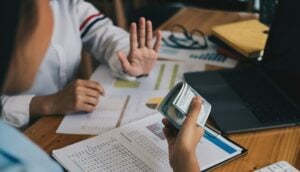 A woman sits at a desk with money and a laptop, diving into the world of digital marketing.
