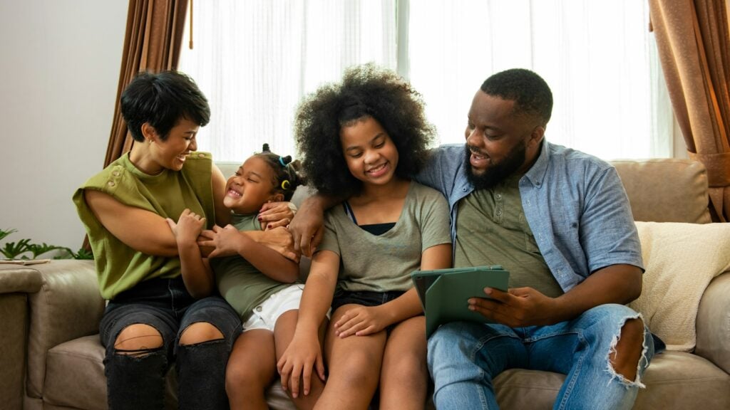 A safe family activity as kids enjoy playing Roblox on a tablet while sitting on a couch.