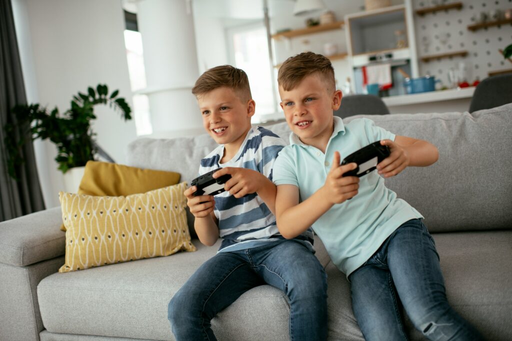 Two kids on a couch enjoying Roblox, a safe online game.