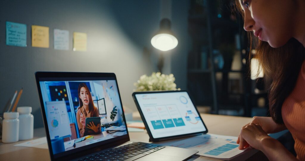 A Woman Is Looking At A Laptop Screen With A Woman On It, Exploring Passive Income Ideas For Financial Freedom In 2024.