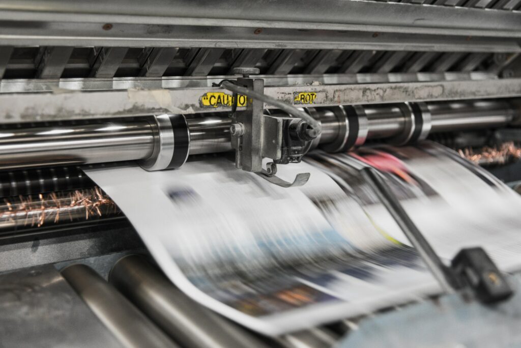 A Newspaper Is Being Printed On A Machine, Symbolizing The Financial Freedom And Potential Passive Income Ideas That Come With The Media Industry.
