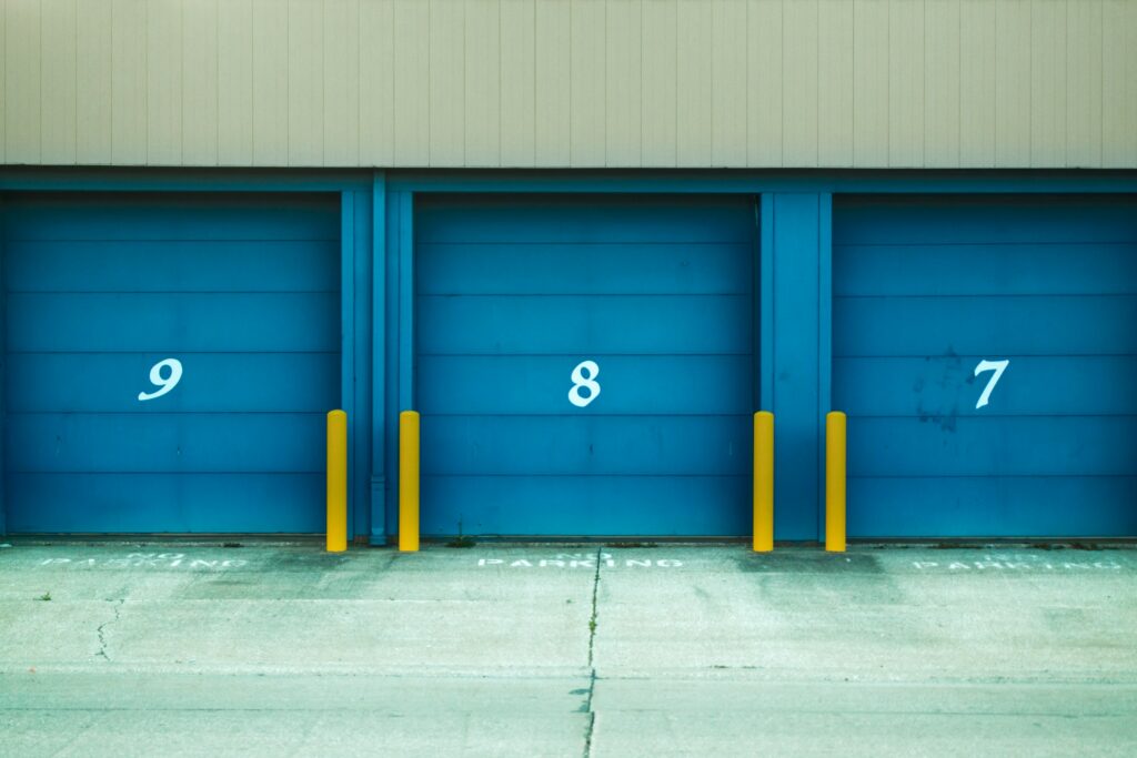 Three Blue Garage Doors With Numbers On Them, Representing Potential Passive Income Ideas For Achieving Financial Freedom By 2024.