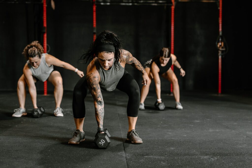 A group of women demonstrating self-discipline while performing kettlebell exercises in a gym.