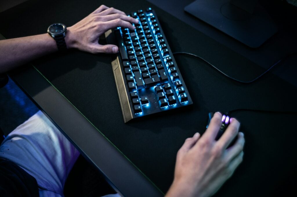 During a deep dive into a coding project, a person's hands are idly typing on a keyboard while engaging with others on Discord.