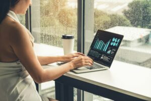 A woman diligently researching CAGR in finance on her laptop while seated in front of a window.