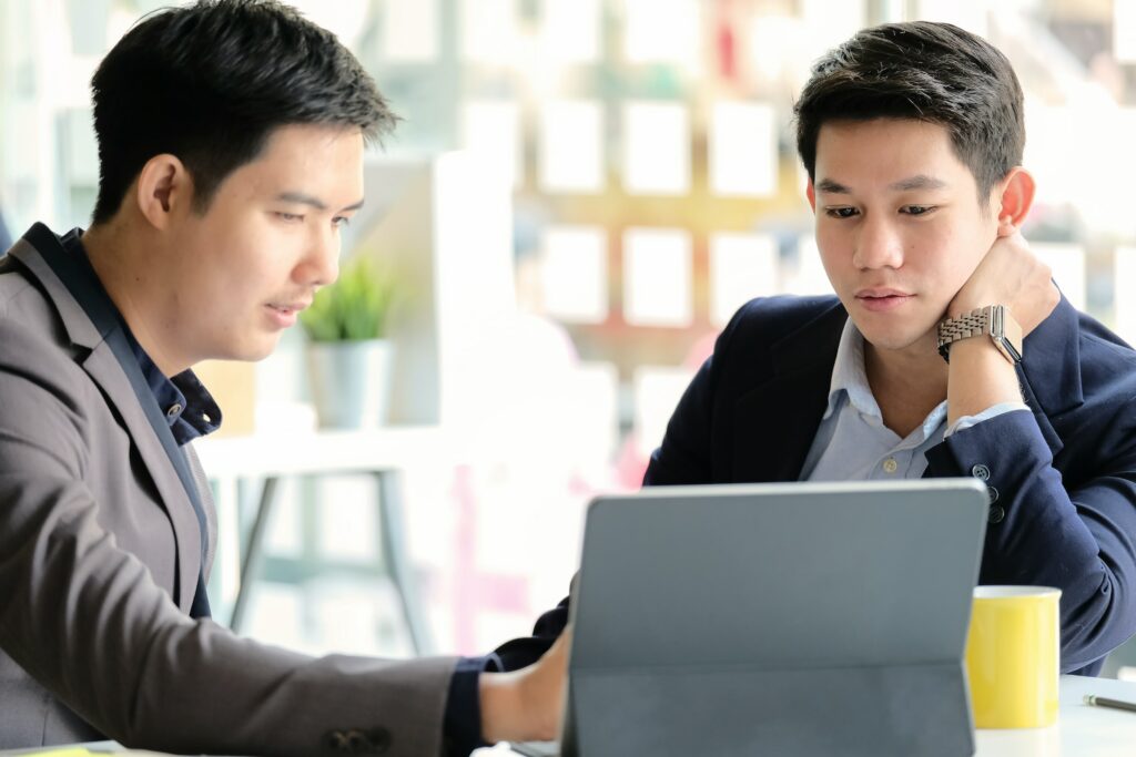 Two asian businessmen looking at a laptop to explore Categorical Data concepts.