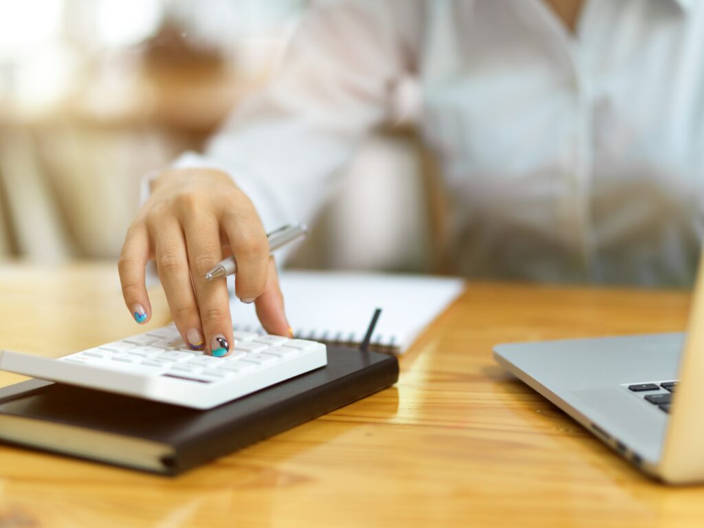 A woman is using a calculator on a desk to navigate through a Cash Flow Crunch.