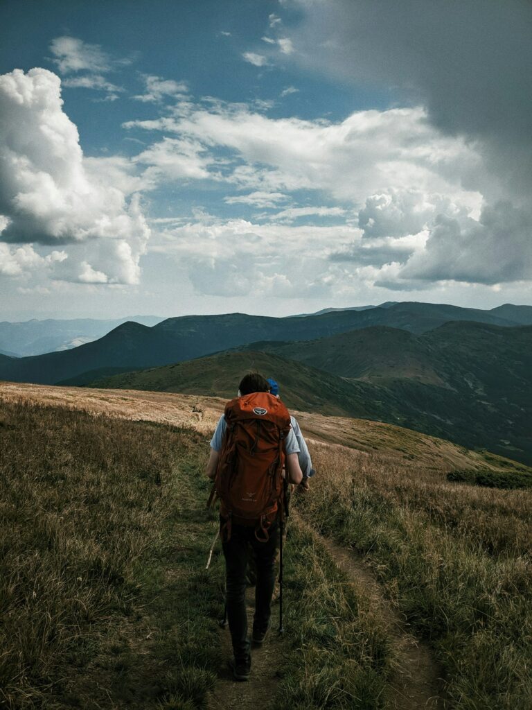 A Man Exploring Wonders While Hiking With A Backpack In The Mountains.