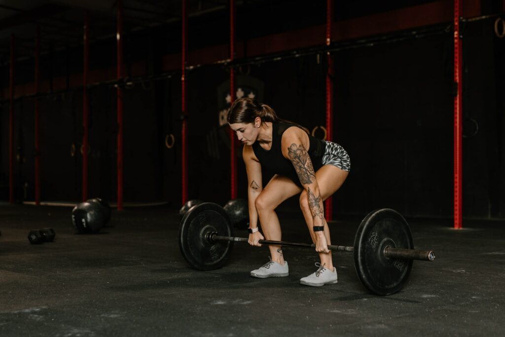 A woman lifting a barbell in a crossfit gym, showcasing strength and determination.