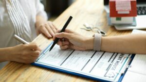 A person signing a comprehensive document at a desk.