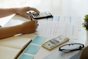 A person is sitting at a desk with papers and a calculator, likely dealing with car insurance or Green Slip in Australia.