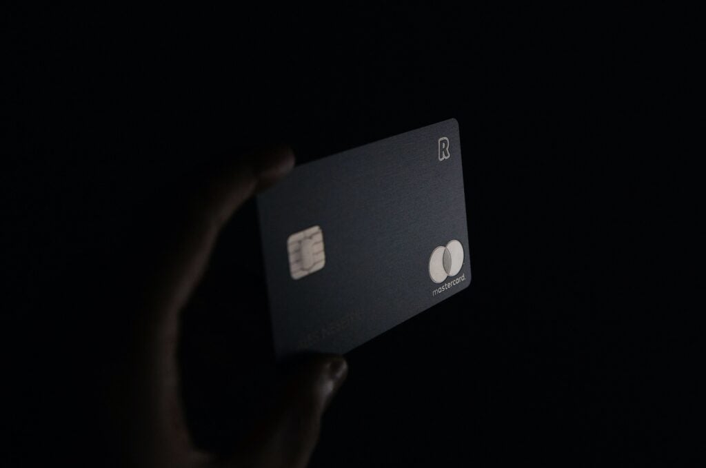 A person holding a credit card while making split payments on Amazon in the dark.