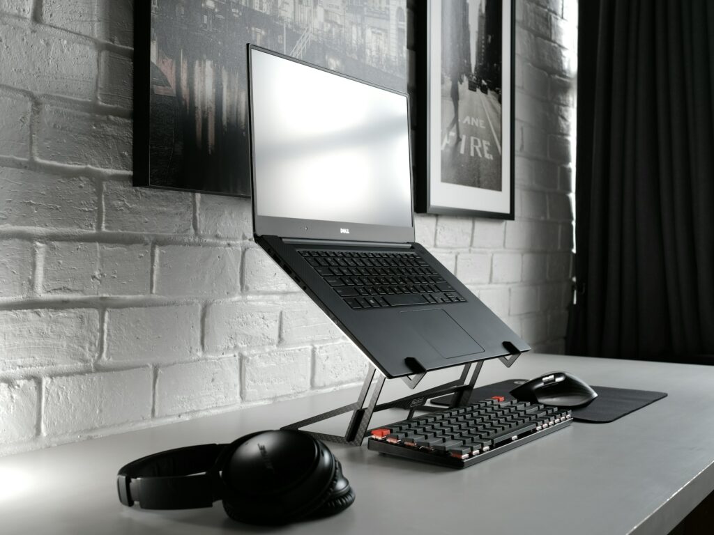 A laptop, one of the essential home office tools for 2024, sits on a desk accompanied by a keyboard and mouse.