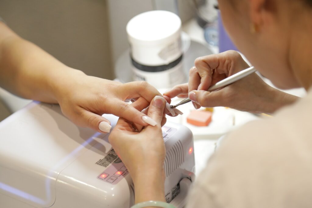 A Woman Receiving Nail Services From A Skillful Nail Tech At A Salon.