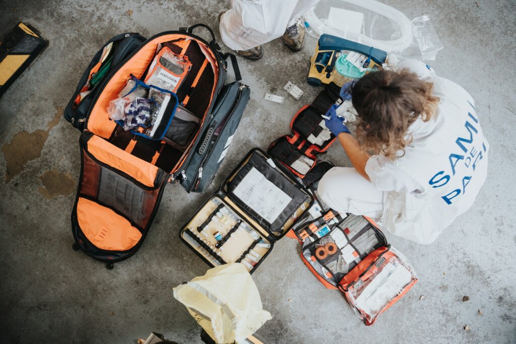 A paramedic is meticulously organizing a bag of medical equipment using a comprehensive guide.