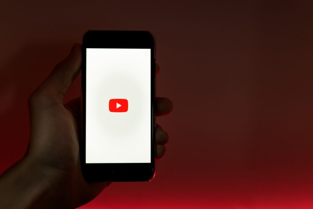 A person holding a smartphone with the YouTube logo on it, accessing videos on the Block Content platform.