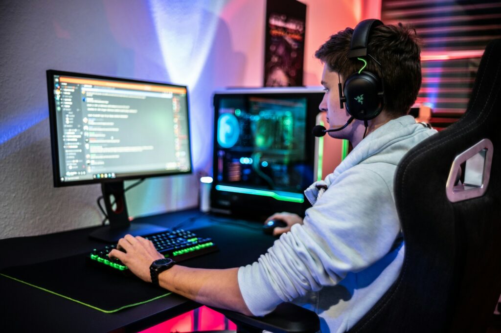 A man sitting in front of a computer playing a game while engaging with the Discord community to make a poll.