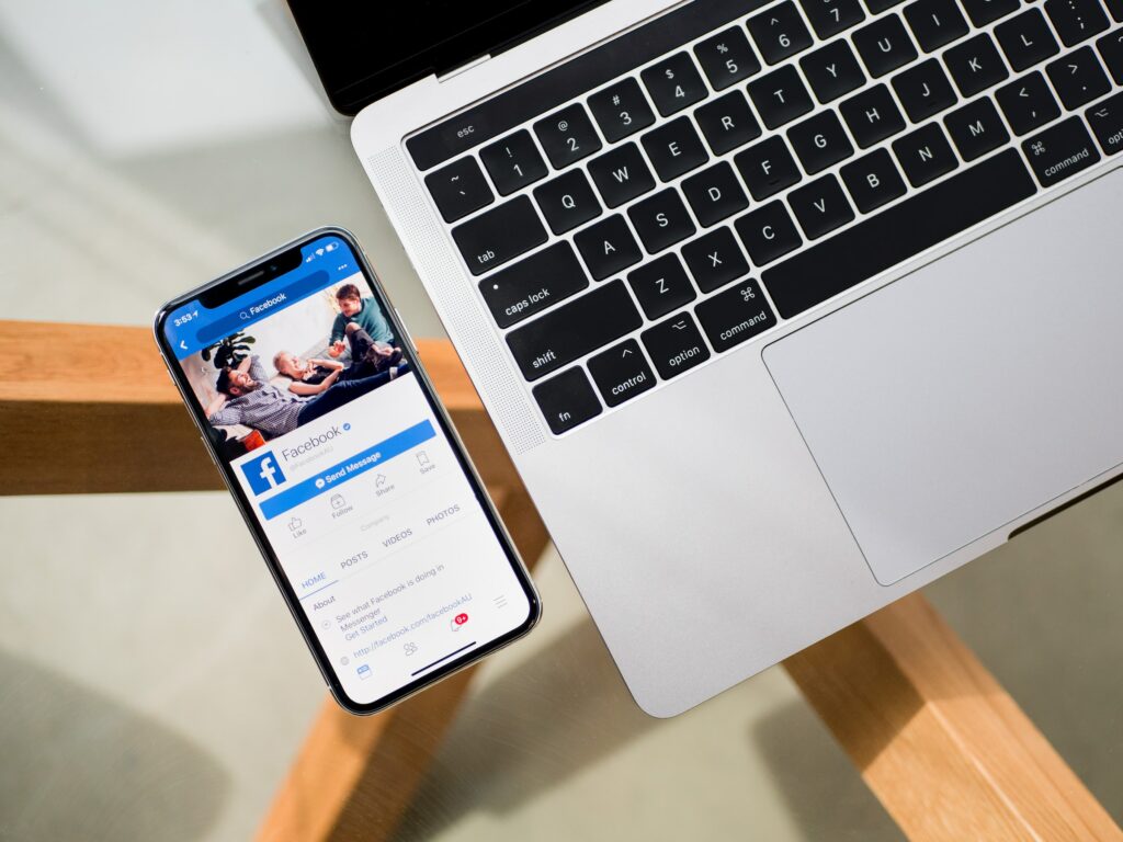 A laptop with a phone on it next to a wooden table provides a comprehensive guide for audience overlap in Facebook ads.