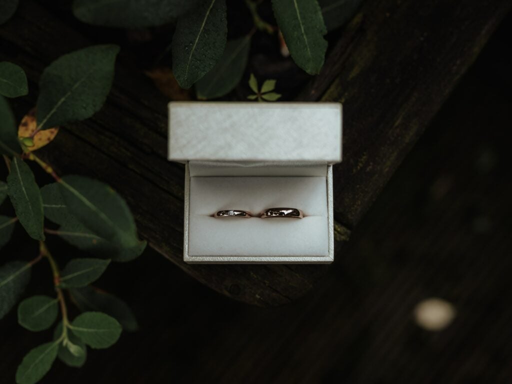 Two wedding rings in a jewelry box on a wooden table, portraying the essence of starting a jewellery business.