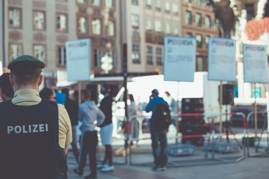 A police officer is ensuring client confidentiality by standing in front of a crowd of people.