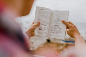 A woman overlooking the ocean while reading a book.