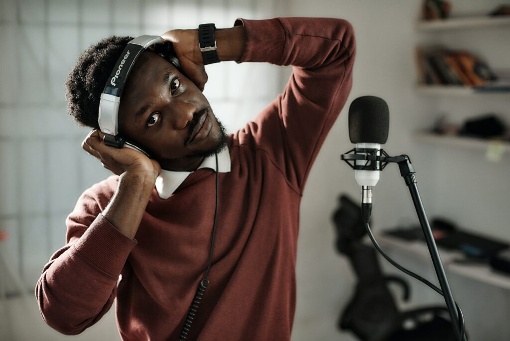 A black man utilizing effective SEO content writing strategies while wearing headphones in front of a microphone.