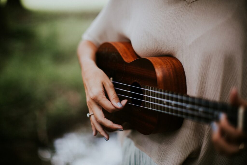 A musician playing ukulele amidst the woods.