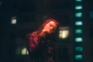 A woman in a leather jacket is standing in front of a building at night, capturing Gen Z's attention with YouTube ads.