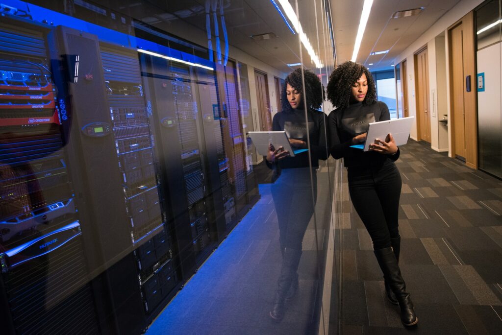A woman is standing in a server room utilizing Google Cloud to amplify efficiency in public sector innovations.