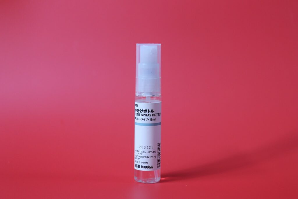 A clear bottle with a white cap on a red background.