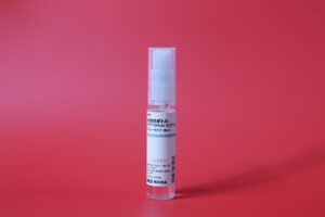 A clear bottle with a white cap on a red background.