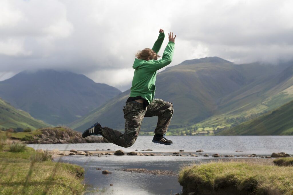 A man jumping in the air near a lake, mastering the marketing strategy.