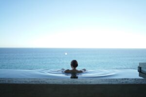 A woman is sitting in a pool overlooking the ocean while unlocking her sales potential with comprehensive digital marketing strategies for Black Friday and Cyber Monday.