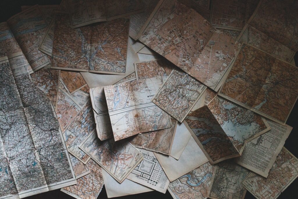A pile of old maps on a table, showcasing superior rankings in search engine visibility through advanced SEO techniques.