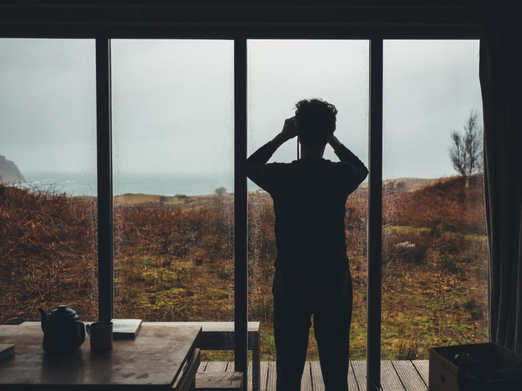 A man mastering SEO by standing in front of a window looking at the ocean.