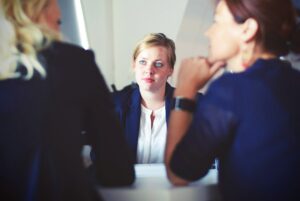 Three women talking to each other at a table. (keywords: table, talking)